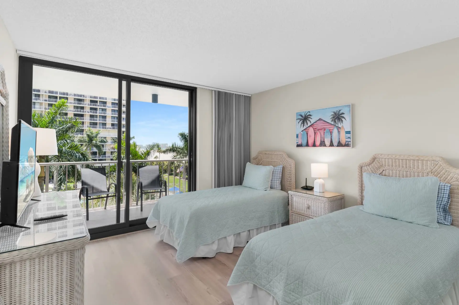 Second bedroom with two twin beds, wicker headboards and balcony access